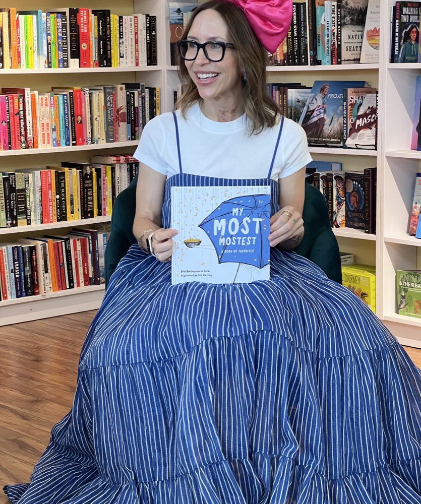 Elle Harting holding up a copy of My Most Mostest at a bookshop reading